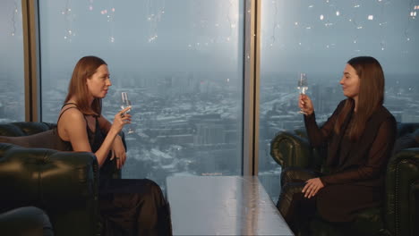 two women enjoying drinks with city view