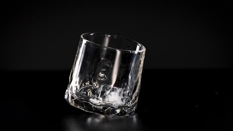 el cubo de hielo aterriza en un vaso de vidrio.