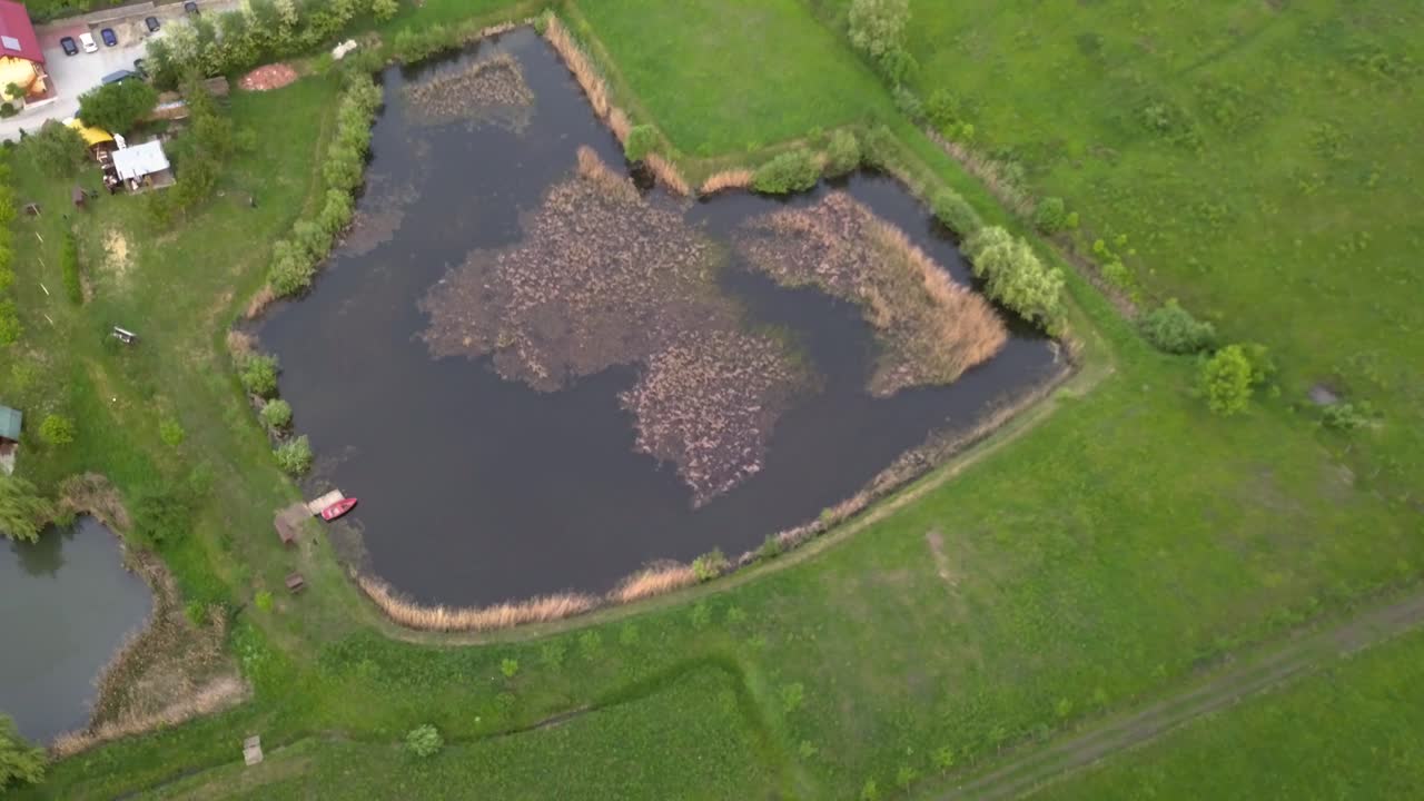 fotografía aérea media de un estanque de pesca rodeado de prados verdes y una casa con un techo rojo, transilvania, rumania - inclinarse hacia abajo y suavizar el pan