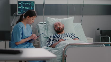 sick man sitting in bed with oxygen tube explaining sickness symptom to medical nurse