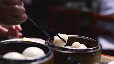 chopsticks picking shrimp dumplings from a steamer