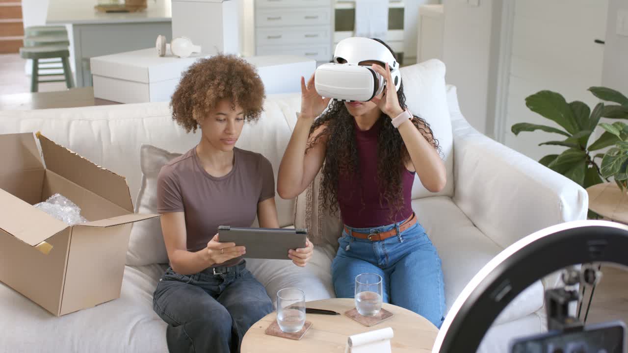 African American female friends unboxing headset from box, following tablet setup and testing VR