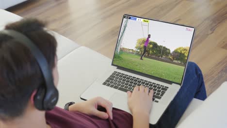 Video-of-caucasian-man-sitting-on-sofa-and-watching-football-on-laptop-at-home