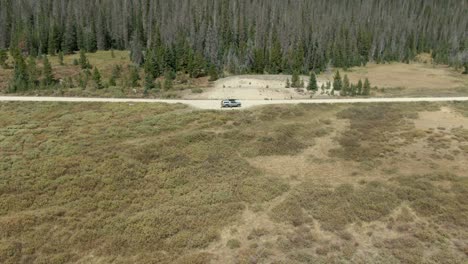 aerial of guy piloting drone in colorado national forest standing next to truck