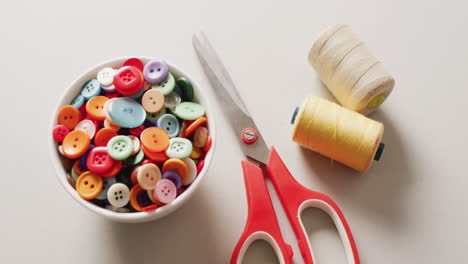 video of scissors with a bowl of buttons and reels of thread on white background