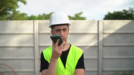 un ingeniero con un sombrero blanco está conversando con otra persona por teléfono - medio de cerca