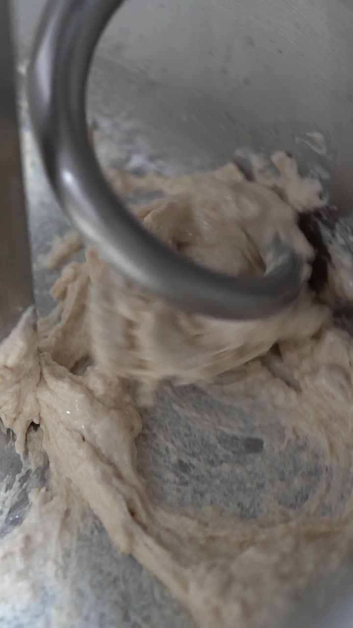 A chief Kneads the dough by a machine to make Italian pizza, close up shot, insert shot