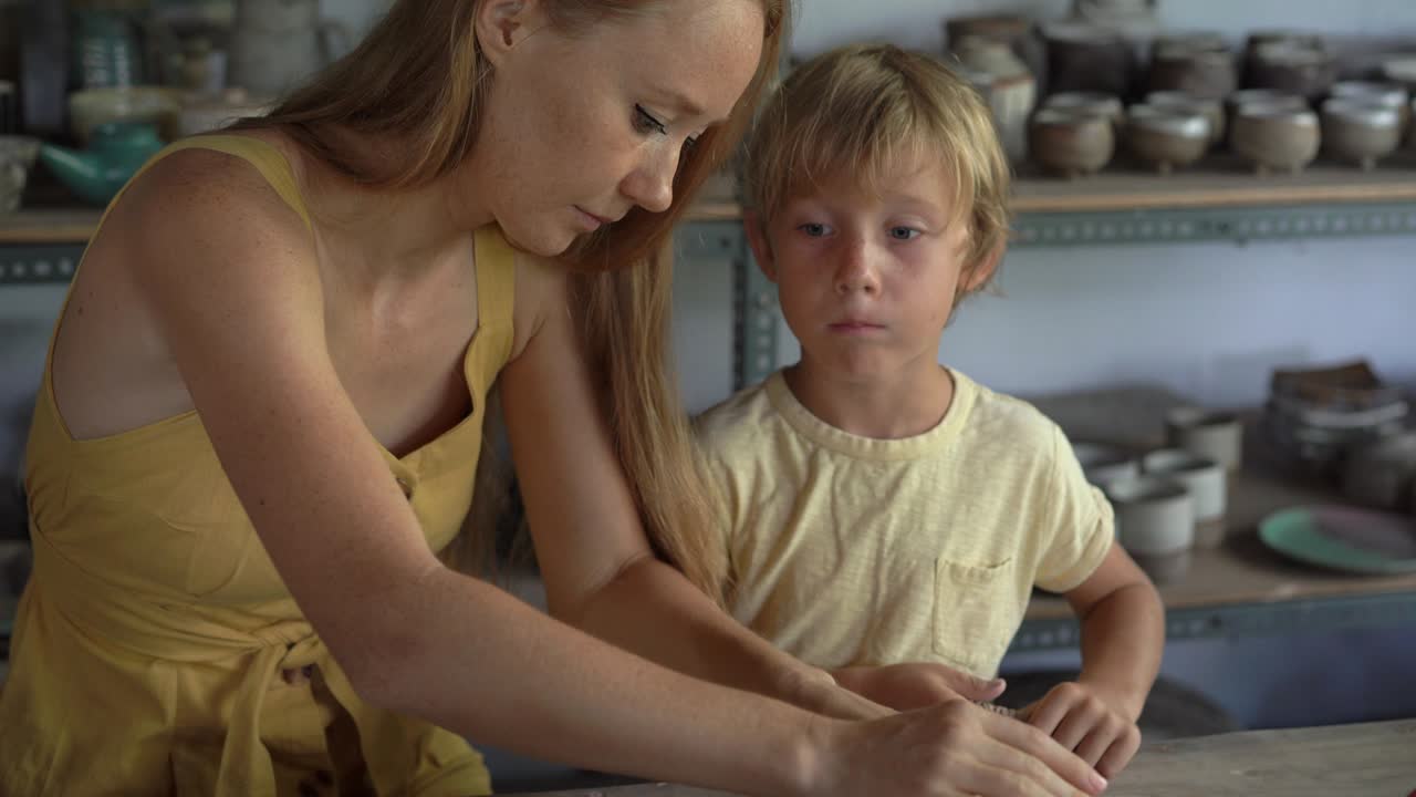 한 젊은 여성 과 그 의 작은 아들 이 도자기 제작 과목 을 하고 있다