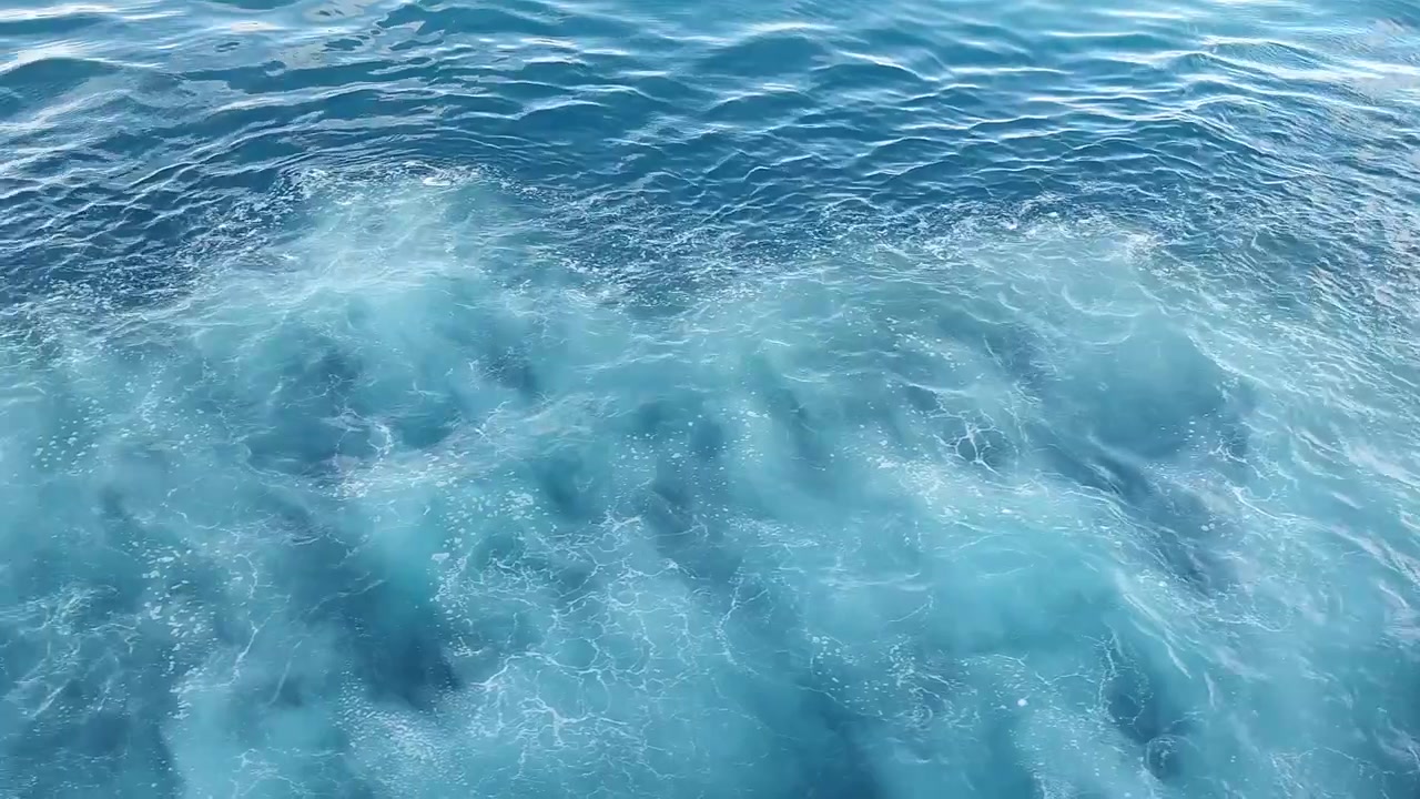 Schiuma bianca che si dissolve nell'acqua blu profonda dell'oceano