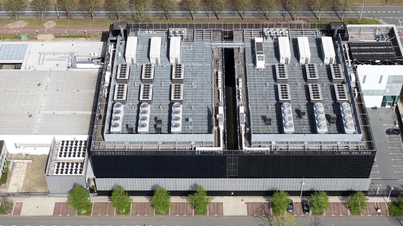 Aerial top down view of a large data center, showing the extensive cooling systems and hvac units on the rooftop that are crucial for maintaining optimal server operating temperatures