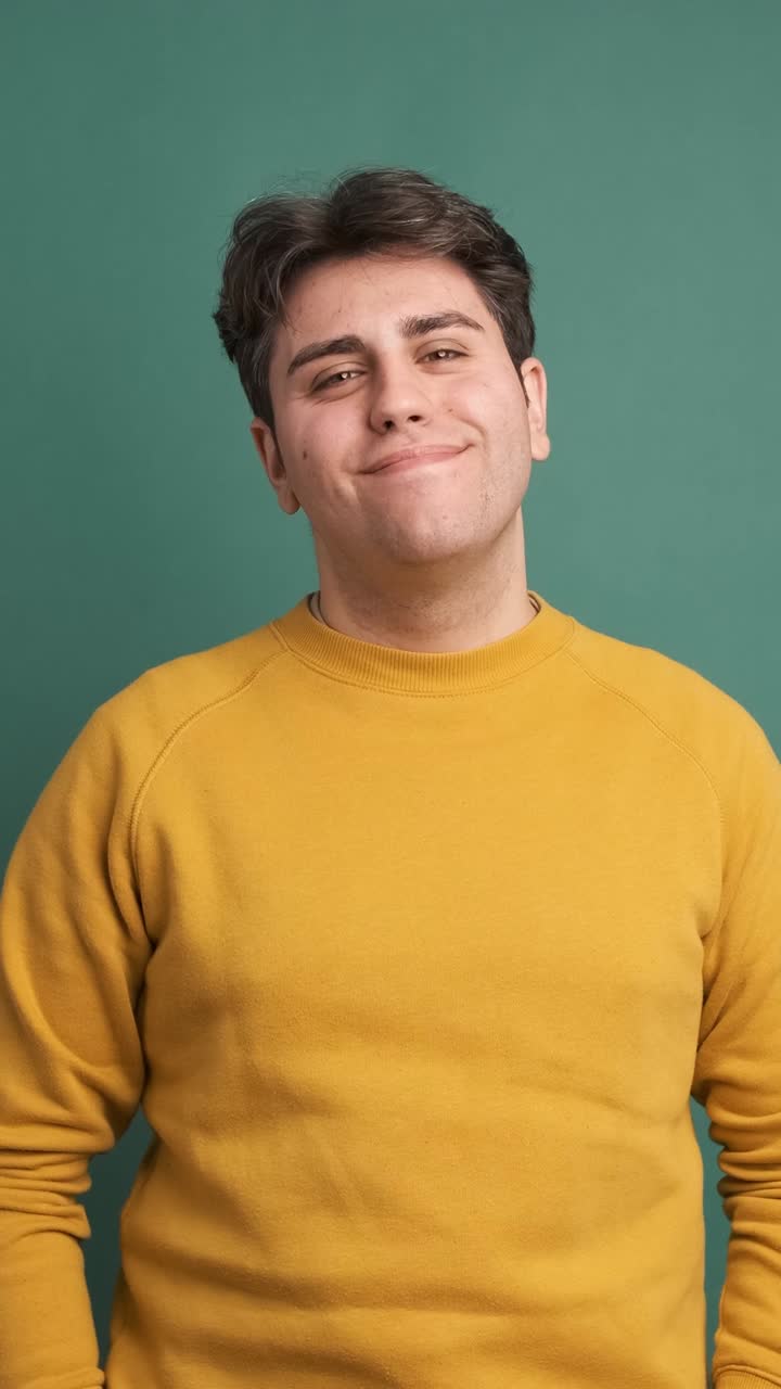Cheerful man in casual clothes standing in green studio