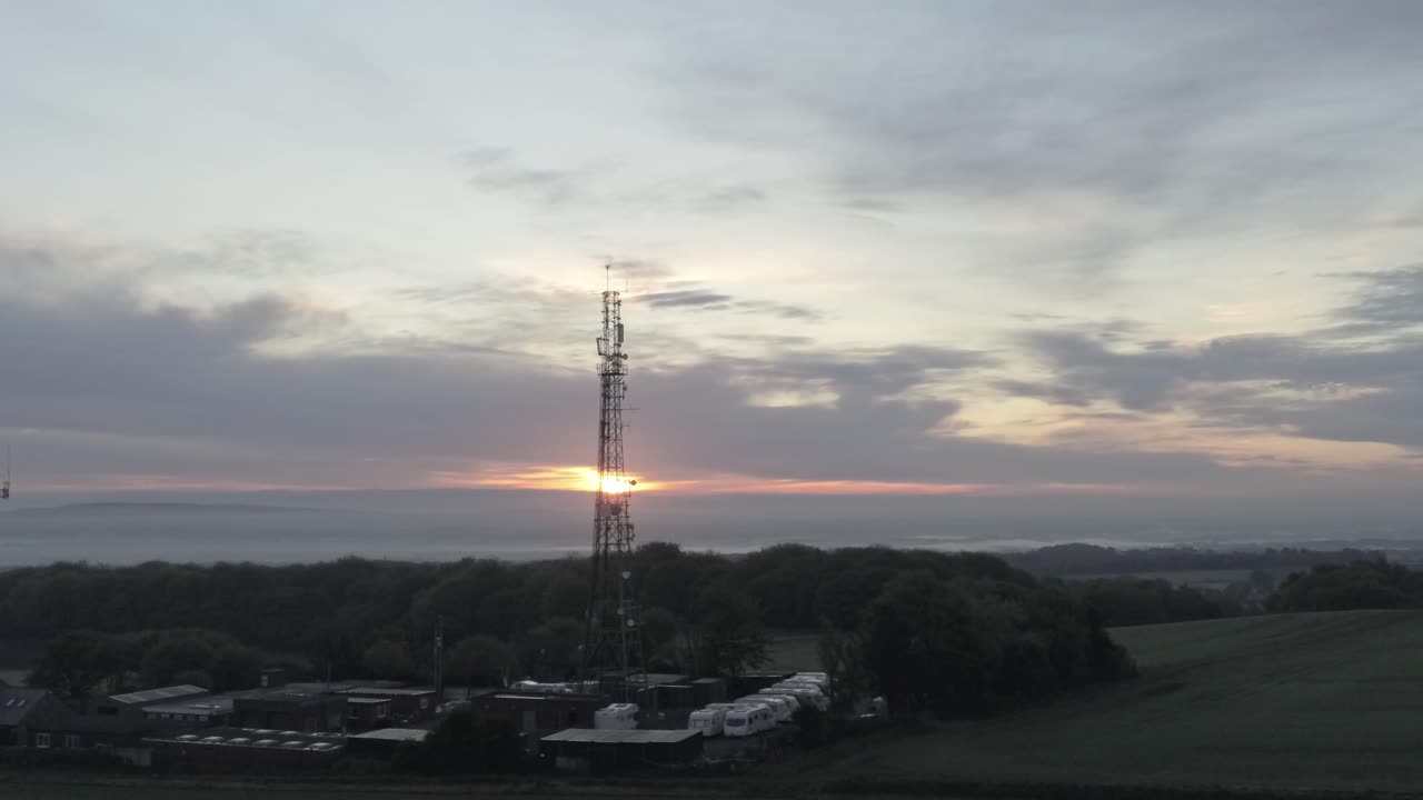 Sunrise lowering in telecom towers aerial view on agricultural farmland at dawn