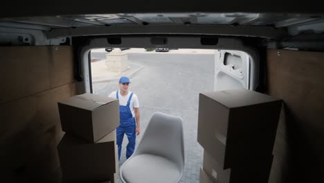 two young workers of removal company are loading boxes and furniture into a minibus