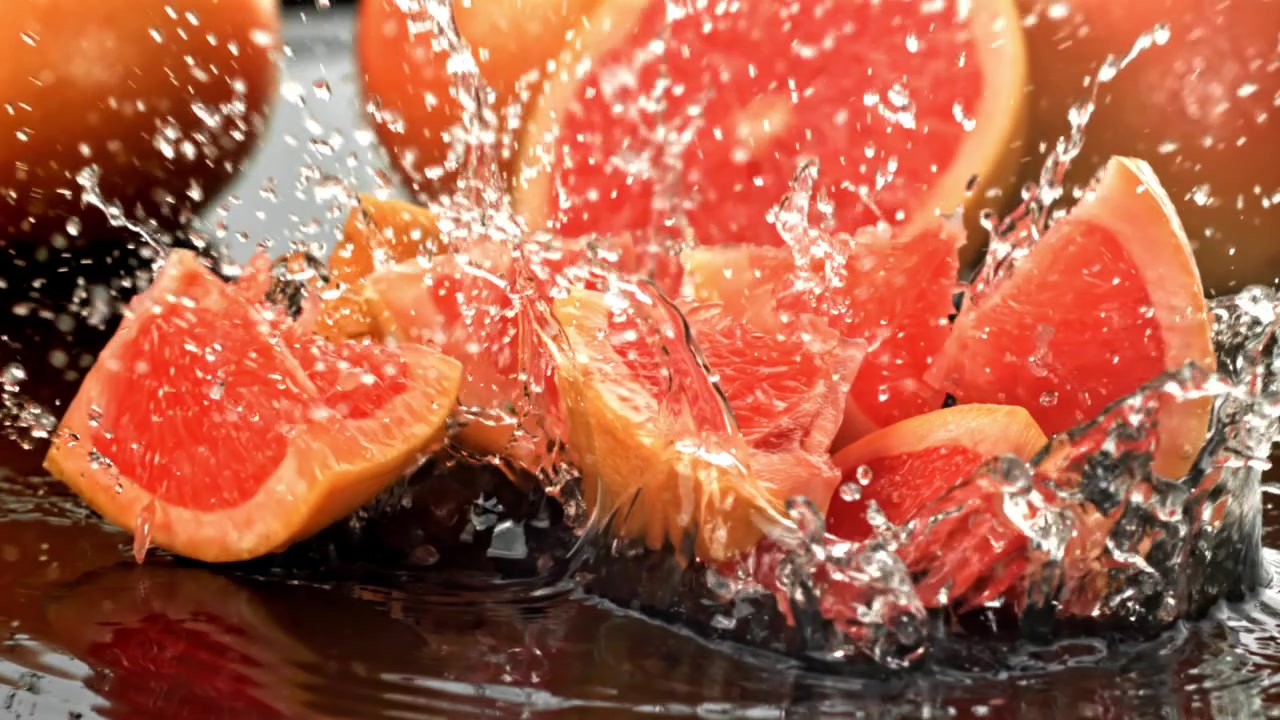 スローモーションで水に落ちるレッドグレープフルーツのスライス