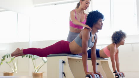 Two-women-practicing-yoga,-one-assisting-other