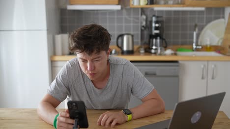 hombre concentrado en el teléfono inteligente en la cocina