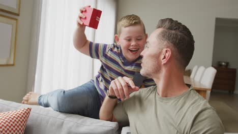 caucasian boy giving a christmas gift to his father at home