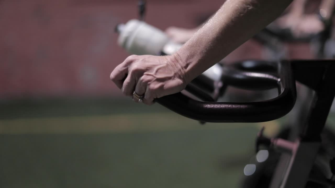 Close-up of hands on stationary bike handlebars during a workout