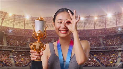 スタジアムでトロフィーとメダルを持った幸せな女性アスリート