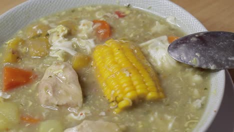 bowl of seasoned soup with shredded chicken, egg and corn in the center, healthy living concept at home