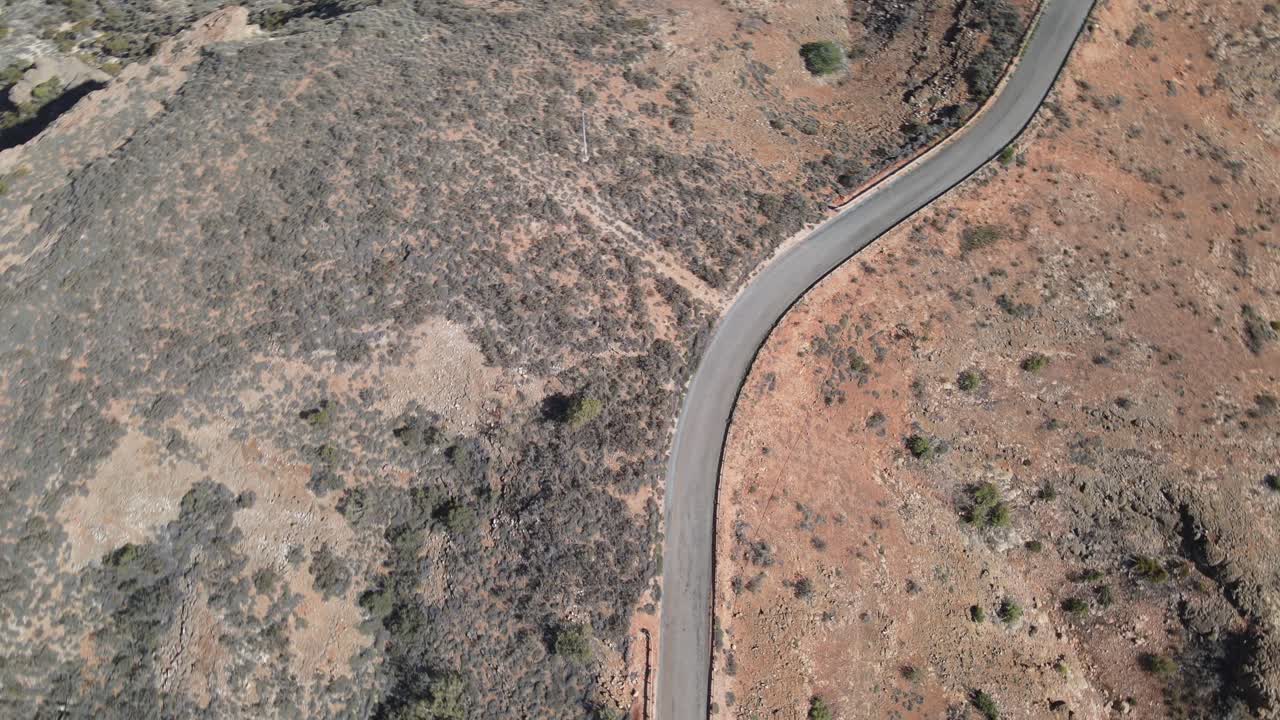 drone pan aéreo hacia abajo girando sobre una carretera en un desierto con arena roja