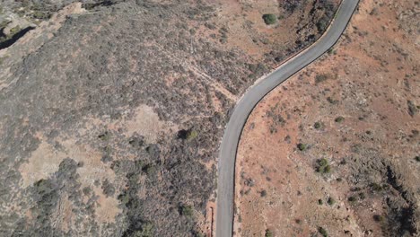 Drone-aerial-pan-down-spinning-over-a-road-in-a-desert-with-red-sand