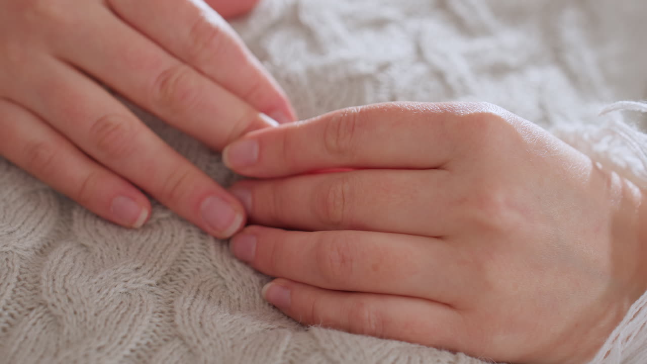 Hands of lady resting palms down on soft blanket while lying down in relaxed position during therapy session conveying calm intimacy vulnerability comfort warmth and healing ambiance