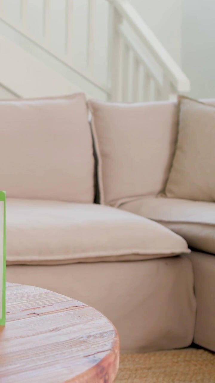 Vertical video: Holding green frame card, woman in pink top placing on coffee table at home to show