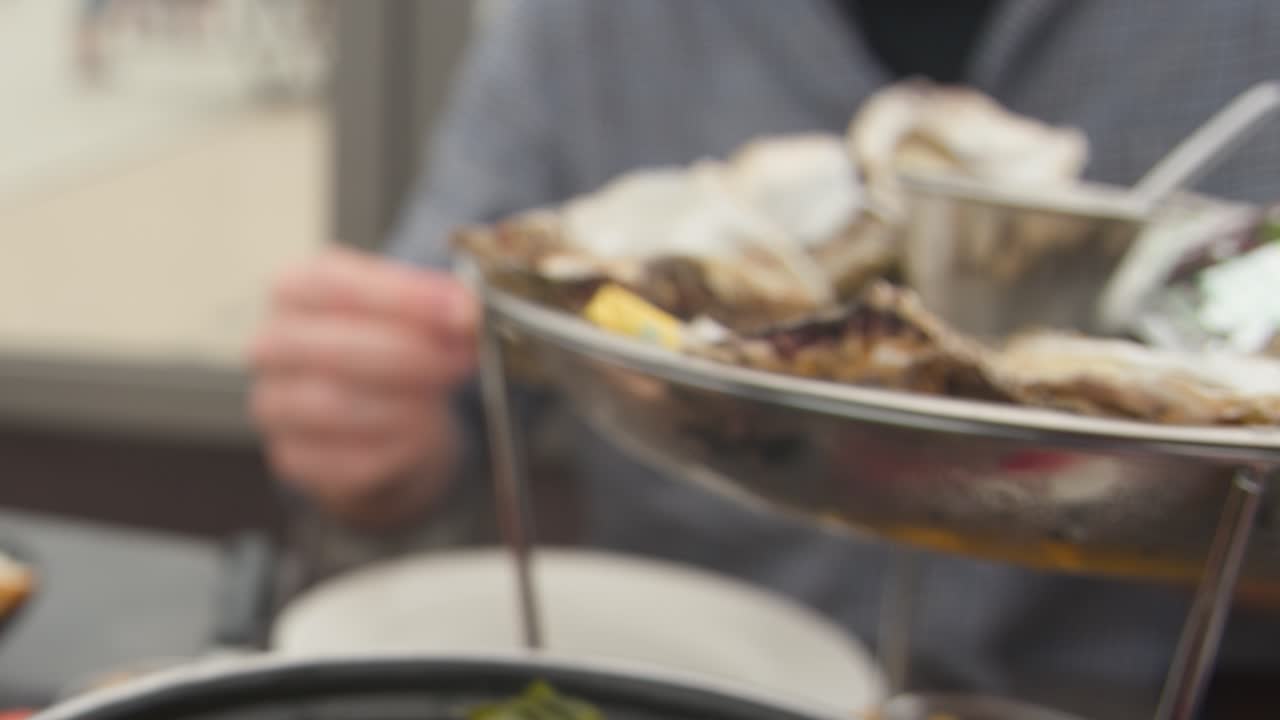 Enjoying mussels, oysters, and fries at an outdoor coastal restaurant in natural daylight