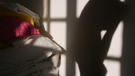 Shadow-of-a-woman-on-white-wall-putting-on-clothes-in-the-room