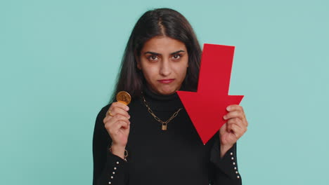 mujer sosteniendo bitcoin y flecha roja hacia abajo, preocupado por el colapso del mercado