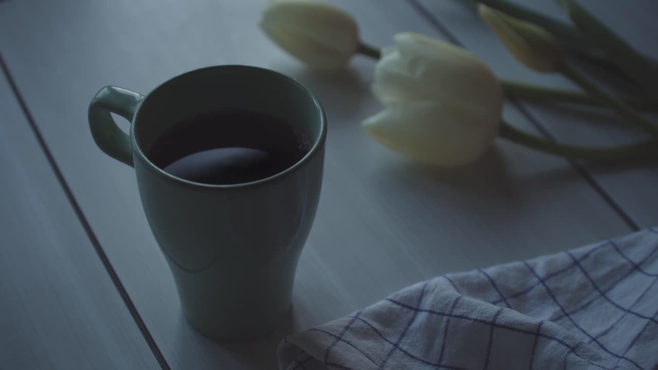 una taza de café con flor de tulipán blanco en la mesa