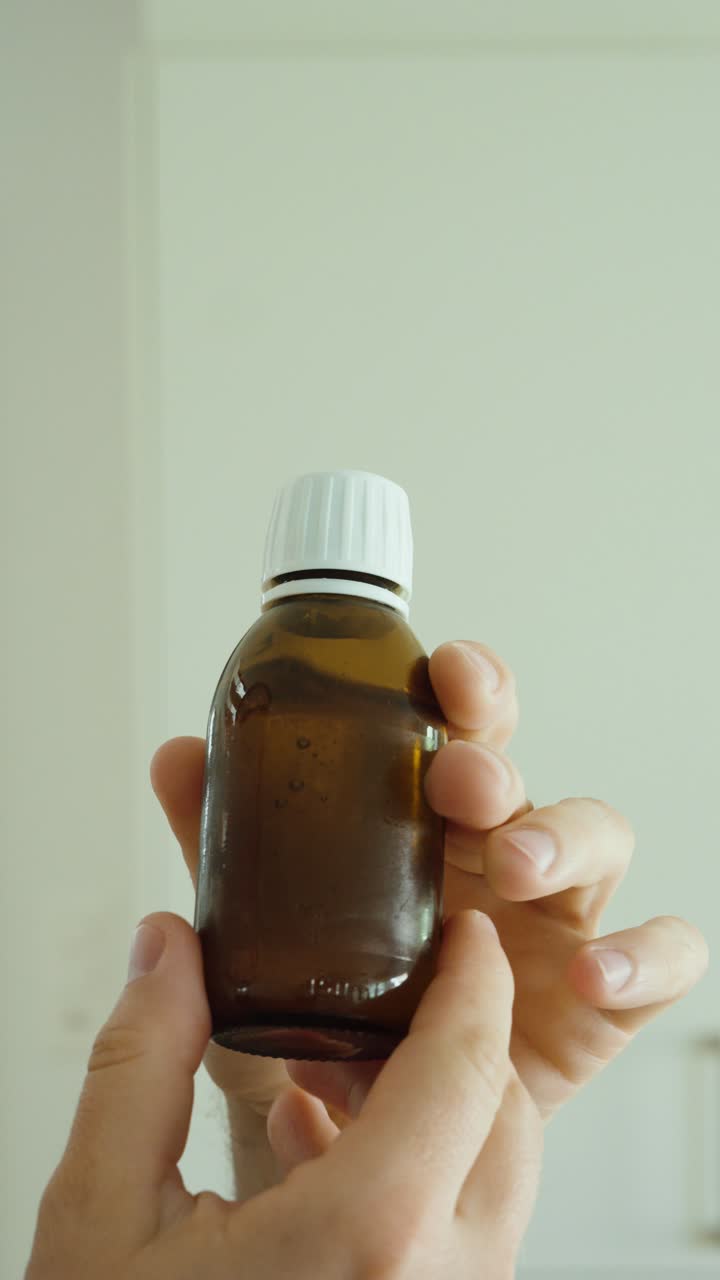 Mano agitando un frasco de medicamento antes de usar, representando preparación, precisión de la dosis y rutina médica