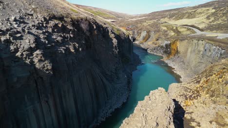 aerial drone forward moving shot over studlagil basalt canyon in iceland on a sunny day