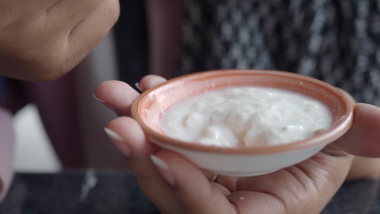 Kvinde spiser en skål yoghurt.
