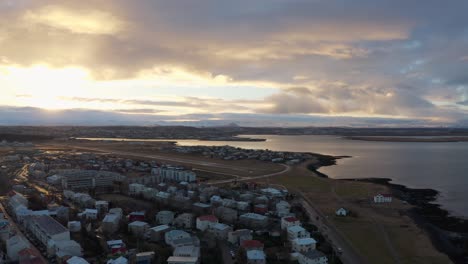 aerial above a small village along coastline in iceland during dreamy sunset