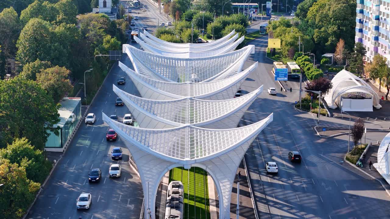 Closeup Aerial View Over the Heroes' Gate Monument in Eroii Revolutiei Square with Morning Traffic Below and a White Tram, Bucharest, Romania