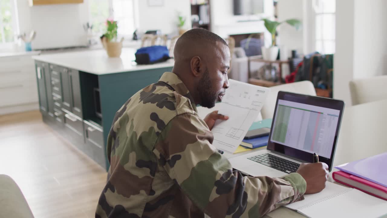 African american father with son sitting at table and working