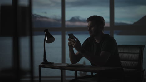 silueta de un hombre sentado en una mesa mirando un teléfono móvil pensando y analizando el mercado de valores resolviendo problemas personales reembolso de préstamos banca por internet