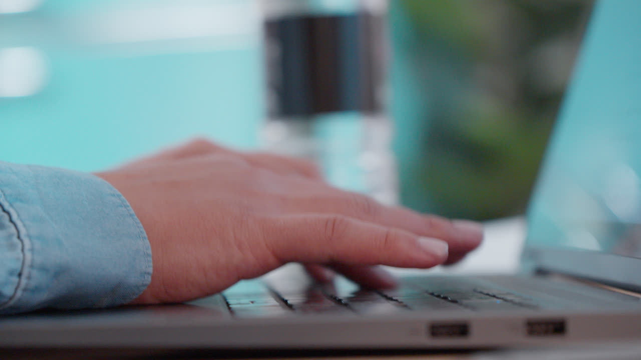 Primo piano delle mani di un impiegato che lavora e digita su un laptop alla scrivania