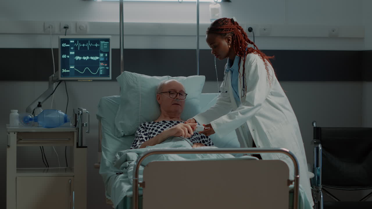Doctor installing oximeter on patient hand in hospital ward