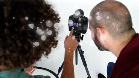 manchas blancas contra diversos fotógrafos masculinos y femeninos ajustando las configuraciones en una cámara digital