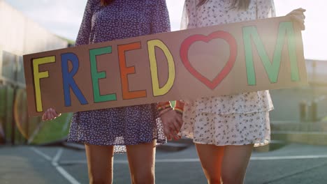 video of two women standing with billboard and holding hands