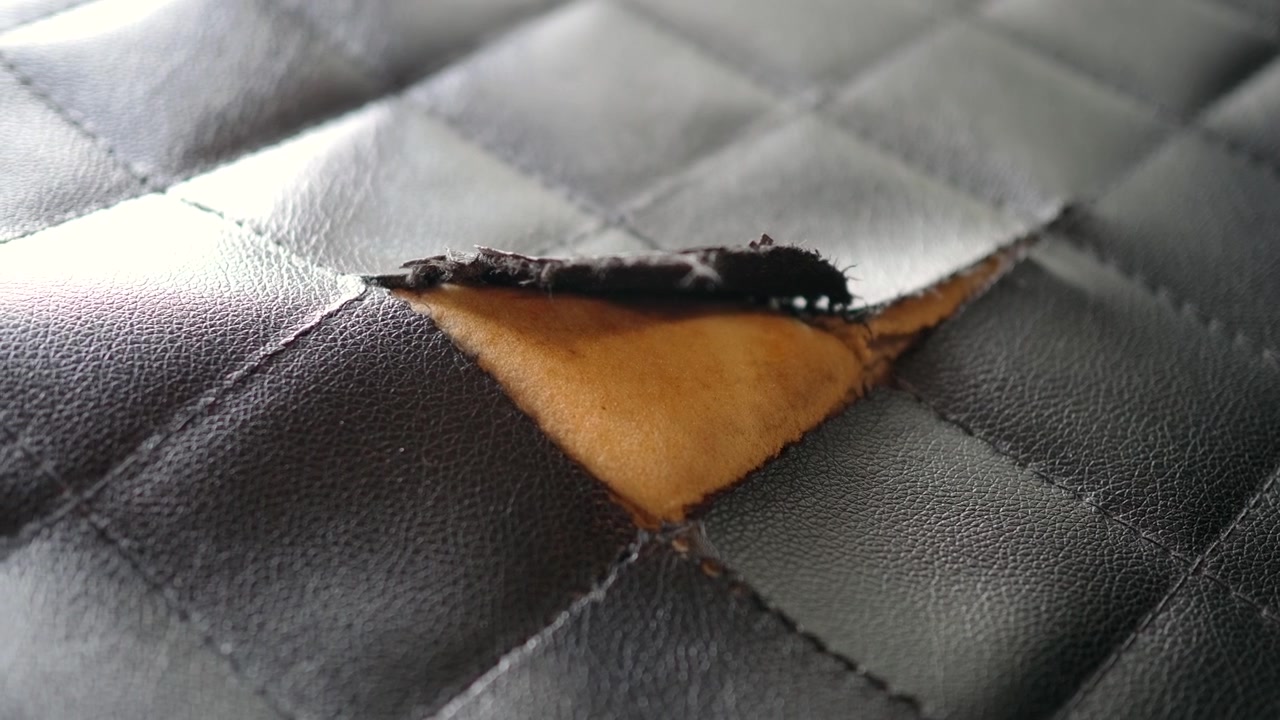 Primer plano de tapicería de cuero acolchado negro dañada