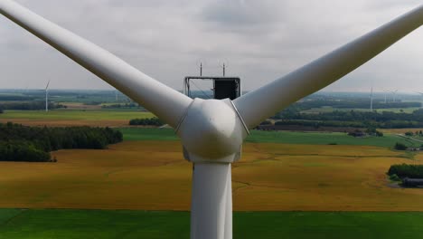 wind turbine propeller blades with an aerial view ascending overhead and farmland in the background