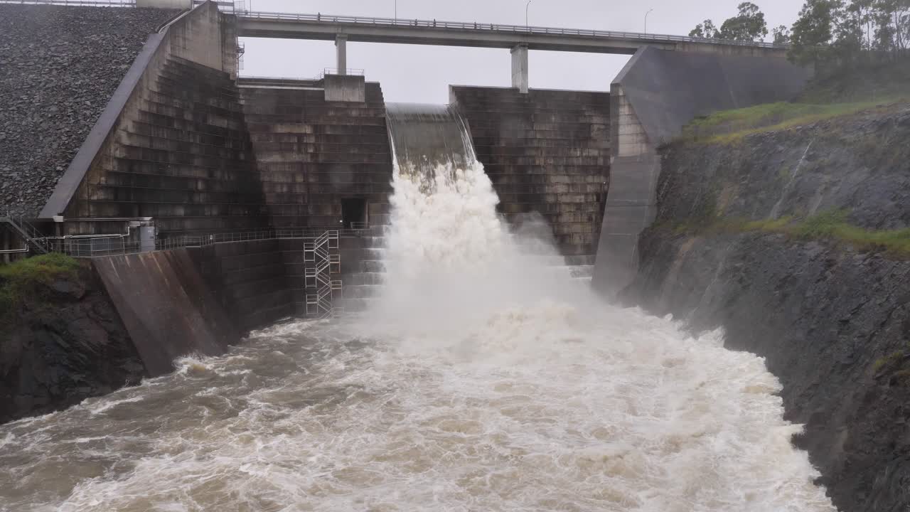 Wide handheld shot of Hinze Dam under heavy rain and water overflow during La Ni&ntilde;a, Gold Coast Hinterland, Queensland, Australia