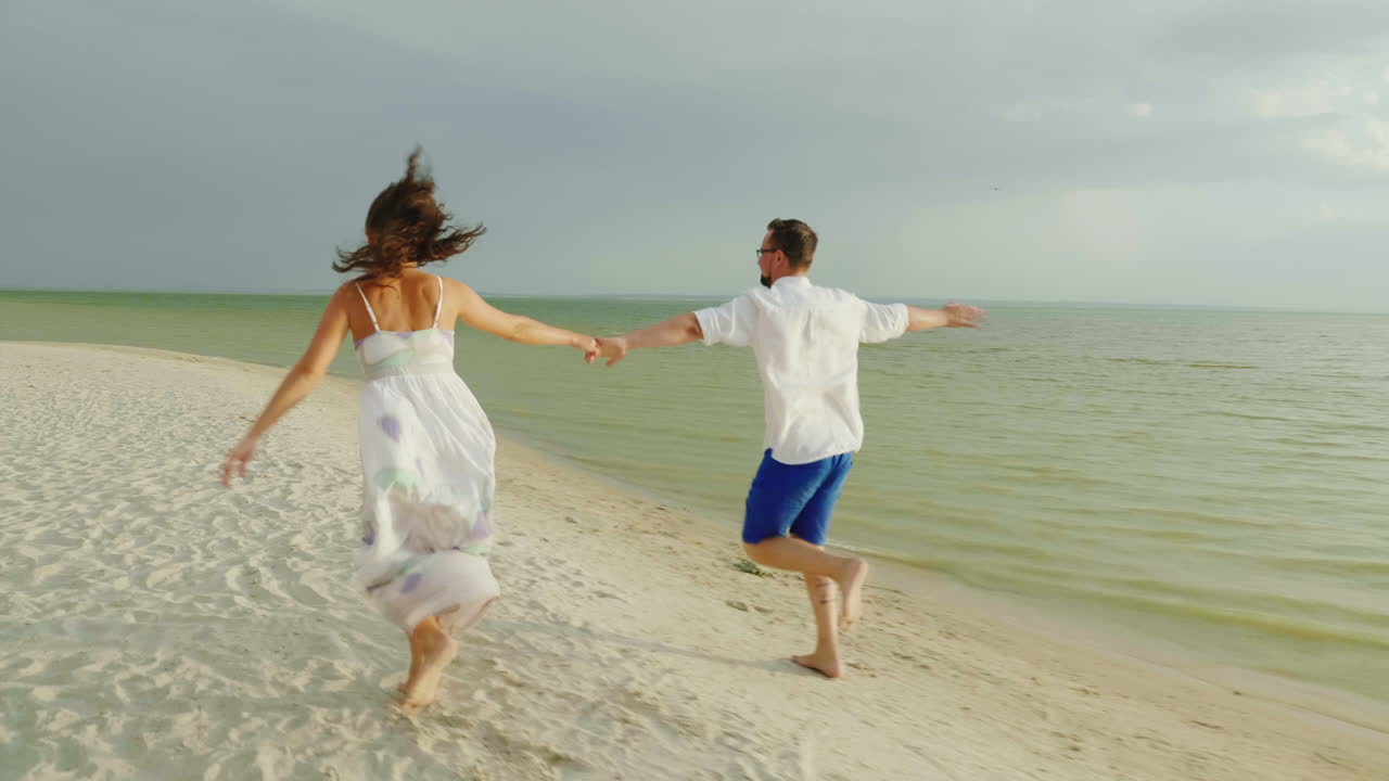 pareja joven enamorada con ropa ligera corriendo despreocupada en una playa tropical limpia