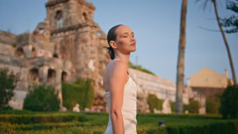 dama sonriente posando castillo disfrutando de la luz del sol de verano de cerca. mujer hermosa