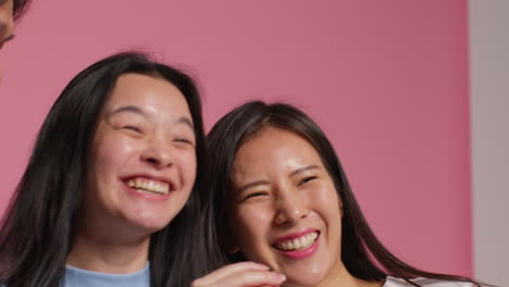 Group-Of-Young-Friends-In-Front-Of-Pink-Studio-Background-Posing-For-Photo-Booth-Style-Portraits-2