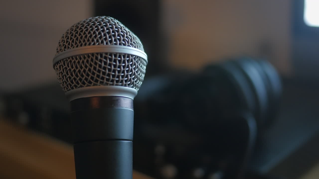A classic dynamic microphone, rotating slowly in a home recording studio. STATIC CLOSE UP SHOT.